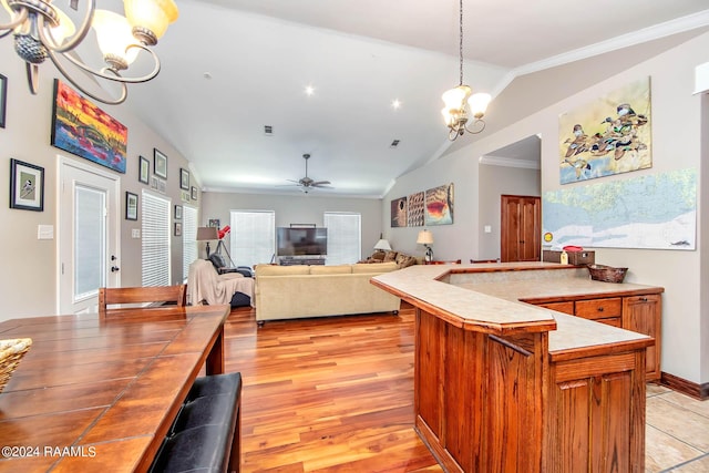 kitchen featuring ceiling fan with notable chandelier, crown molding, decorative light fixtures, light hardwood / wood-style floors, and lofted ceiling