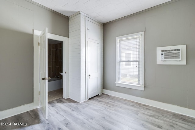 unfurnished bedroom with an AC wall unit and light wood-type flooring