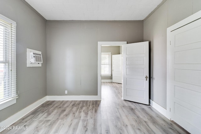 unfurnished room featuring an AC wall unit, ornamental molding, and light hardwood / wood-style flooring