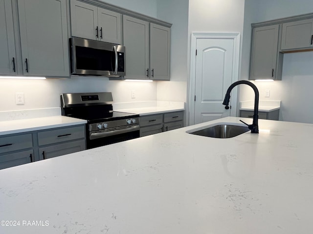 kitchen with appliances with stainless steel finishes, gray cabinets, and sink