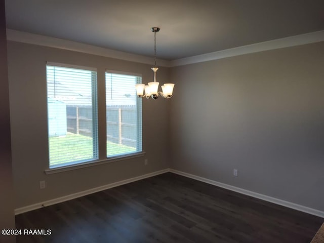 spare room with ornamental molding, dark wood-type flooring, an inviting chandelier, and a healthy amount of sunlight