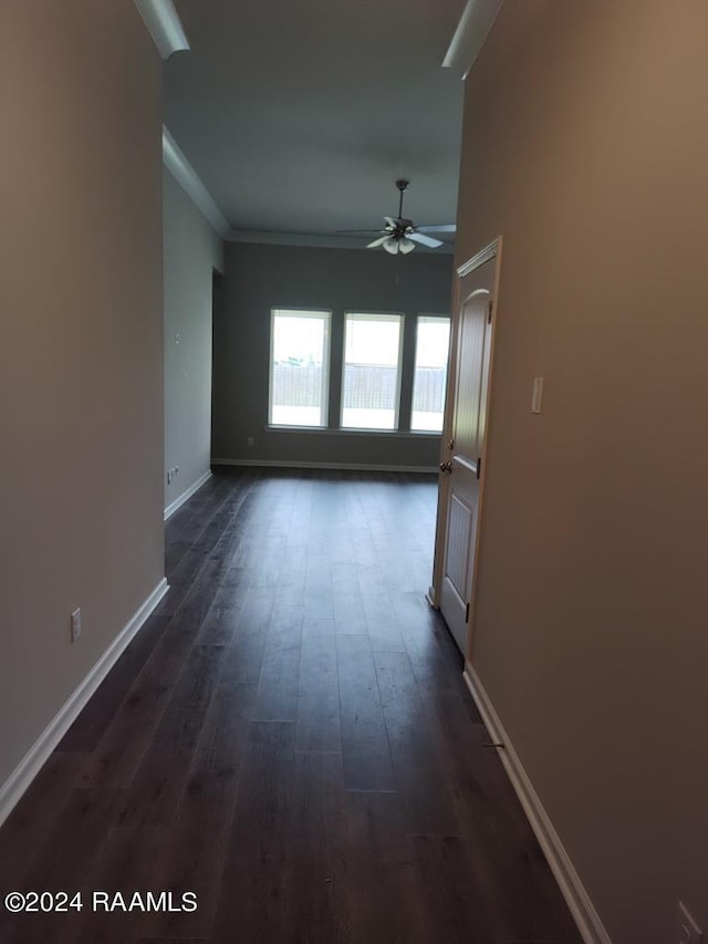 interior space with ornamental molding, ceiling fan, and dark wood-type flooring