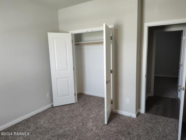 unfurnished bedroom featuring dark colored carpet and a closet