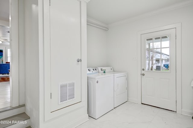 clothes washing area featuring crown molding and washer and dryer