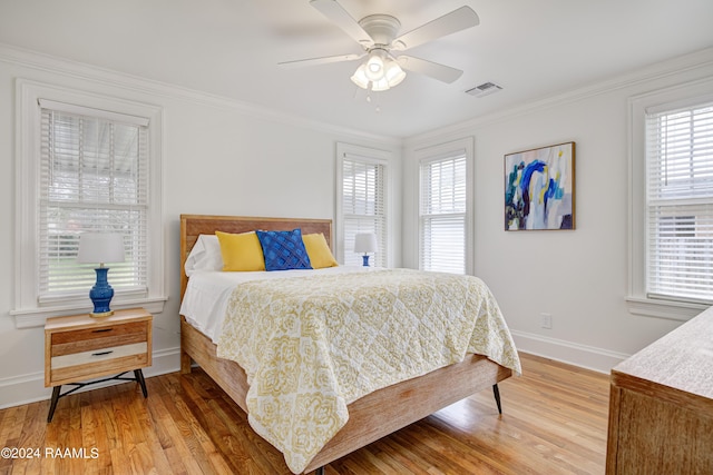 bedroom featuring multiple windows, wood-type flooring, ornamental molding, and ceiling fan