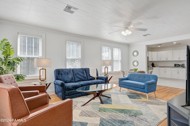 living room with crown molding, ceiling fan, and light hardwood / wood-style flooring