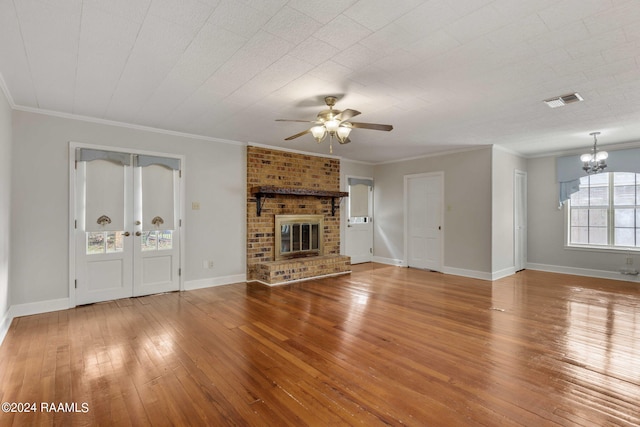 unfurnished living room featuring hardwood / wood-style floors, ceiling fan with notable chandelier, crown molding, and a fireplace