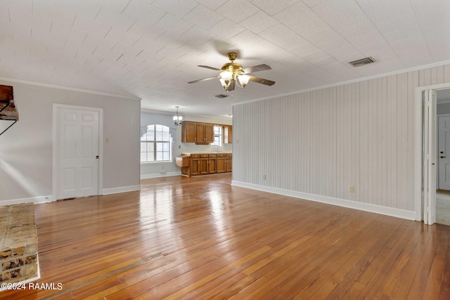 unfurnished living room featuring ceiling fan with notable chandelier, light wood-type flooring, and crown molding