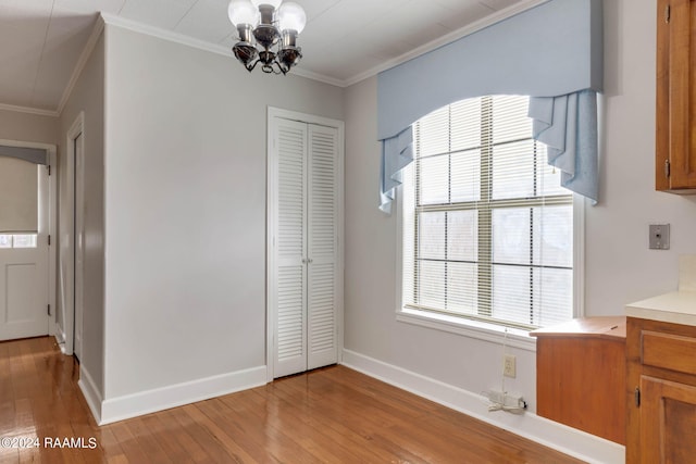 unfurnished dining area with an inviting chandelier, light wood-type flooring, and ornamental molding