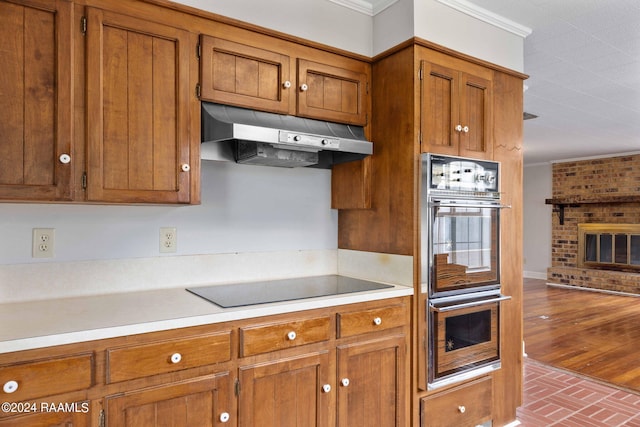 kitchen with a fireplace, black appliances, and ornamental molding