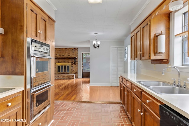 kitchen with black appliances, crown molding, sink, a fireplace, and decorative light fixtures