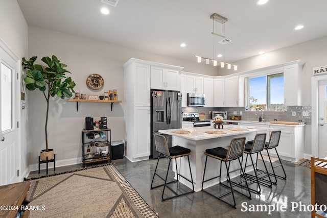 kitchen with white cabinets, a center island, a kitchen bar, stainless steel appliances, and decorative backsplash