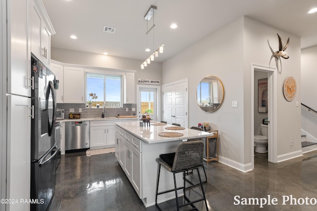 kitchen with a center island, decorative light fixtures, white cabinetry, stainless steel appliances, and sink