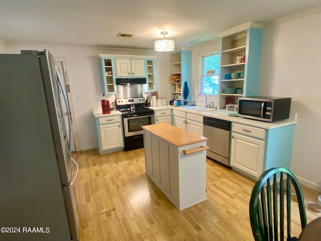 411 Rodney St, Eunice, LA 70535 - kitchen featuring stainless steel appliances, under cabinet range hood, open shelves, and light wood finished floors