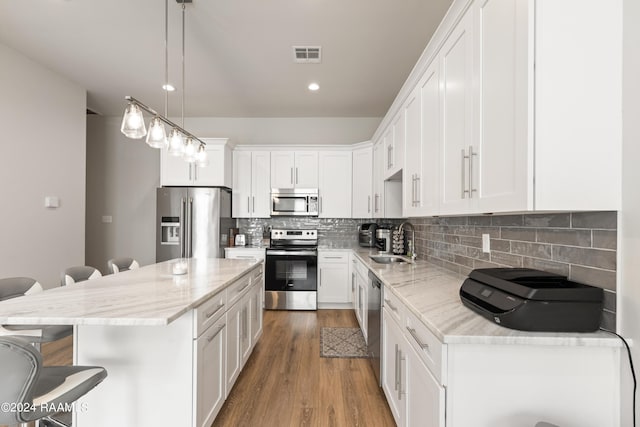 kitchen with a kitchen island, white cabinetry, stainless steel appliances, sink, and hanging light fixtures