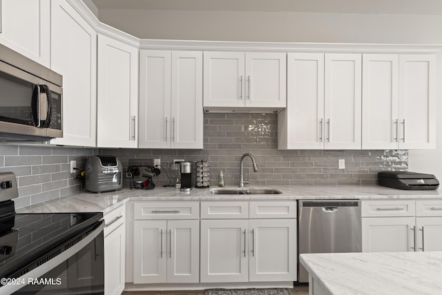 kitchen with decorative backsplash, sink, stainless steel appliances, and white cabinetry