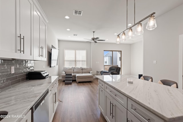 kitchen with ceiling fan, backsplash, stainless steel dishwasher, light stone countertops, and white cabinets