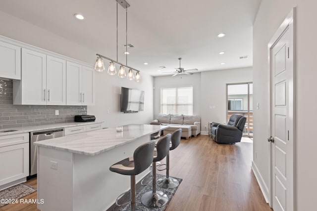 kitchen featuring ceiling fan, dishwasher, a center island, white cabinetry, and a kitchen breakfast bar