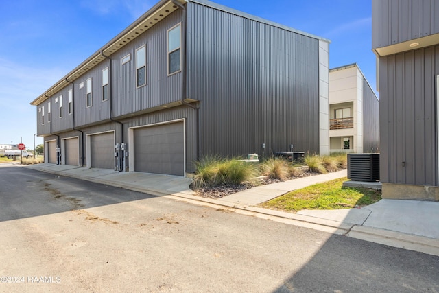 view of property exterior with cooling unit and a garage