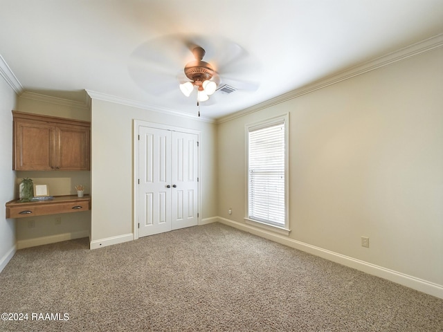 unfurnished bedroom with crown molding, carpet flooring, ceiling fan, and a closet