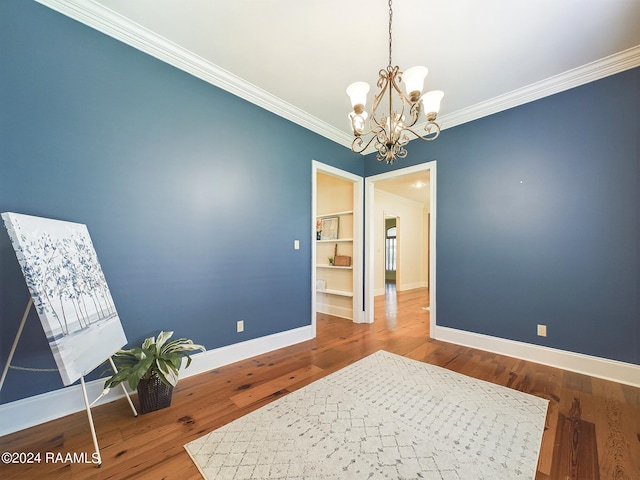 sitting room with built in shelves, ornamental molding, wood-type flooring, and a chandelier