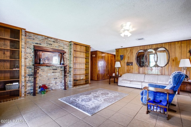 tiled living room with built in shelves, wooden walls, ceiling fan, and a textured ceiling