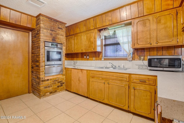 kitchen featuring wood walls, sink, a textured ceiling, and appliances with stainless steel finishes