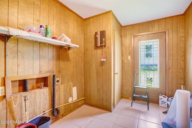 tiled entryway featuring wood walls and crown molding