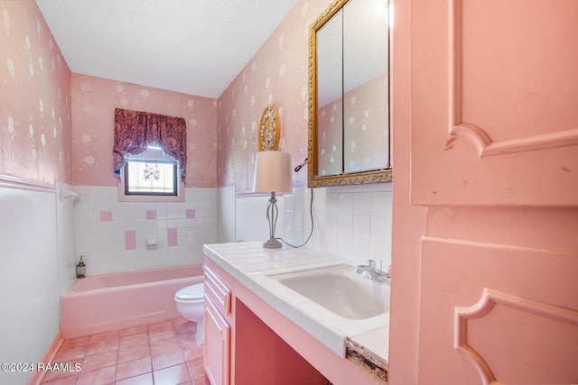 bathroom featuring vanity, a bathing tub, tile patterned floors, toilet, and a textured ceiling