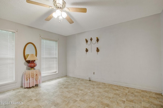 empty room with a textured ceiling, plenty of natural light, and ceiling fan