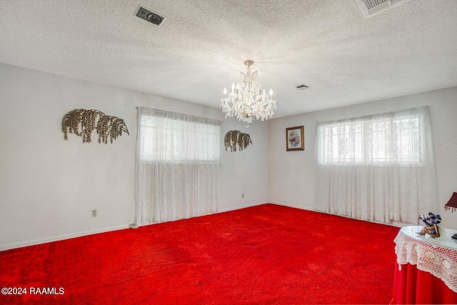 carpeted empty room featuring a chandelier and a textured ceiling