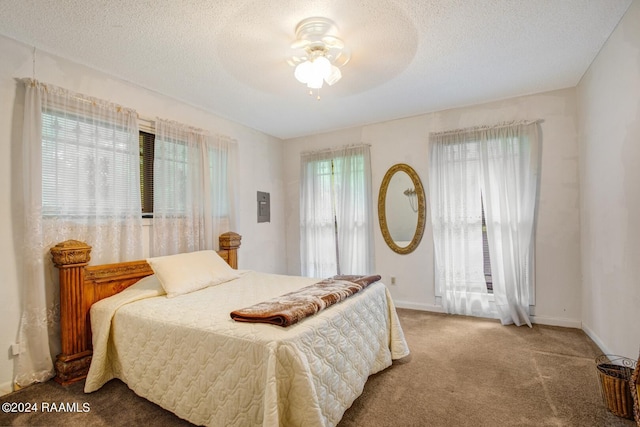 carpeted bedroom featuring ceiling fan and a textured ceiling