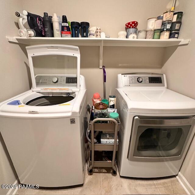 laundry area with washer and clothes dryer and light tile patterned floors