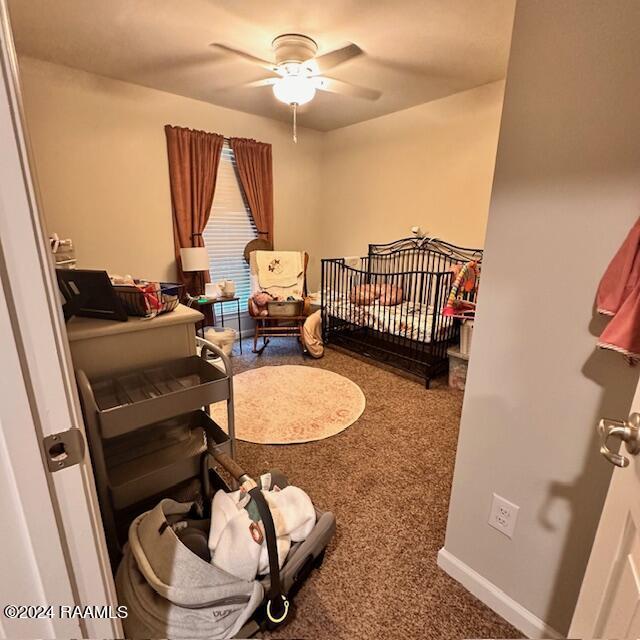 bedroom with a crib, carpet, and ceiling fan