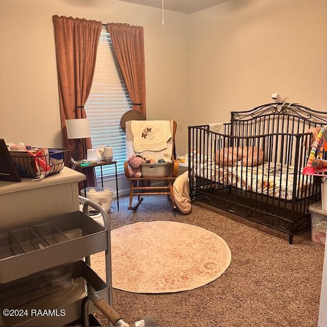 bedroom featuring carpet and a nursery area