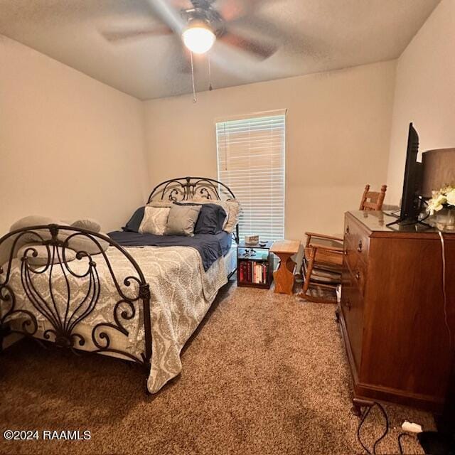 carpeted bedroom featuring ceiling fan and a textured ceiling