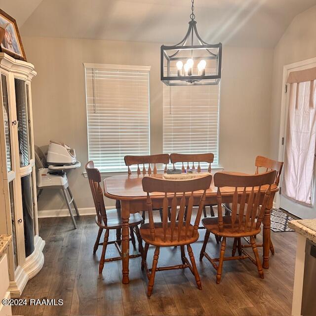 dining space featuring dark hardwood / wood-style flooring, an inviting chandelier, and lofted ceiling