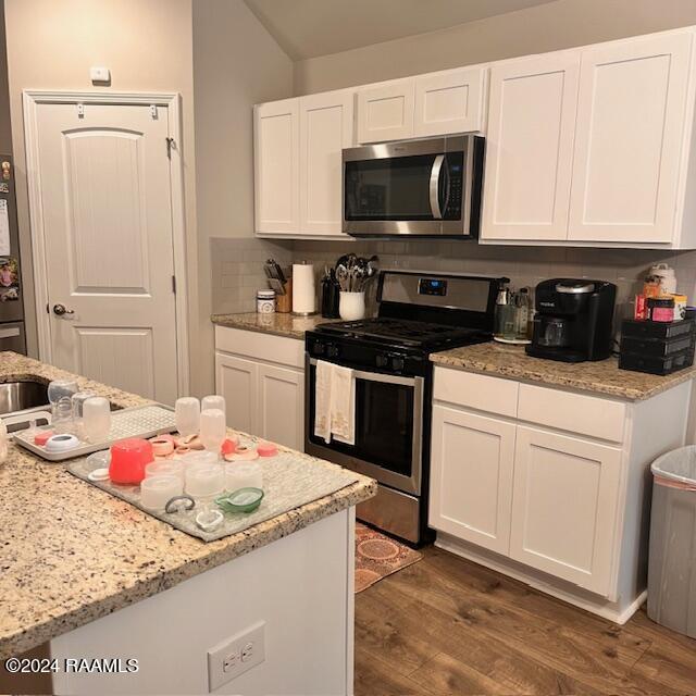 kitchen with decorative backsplash, white cabinetry, stainless steel appliances, and dark wood-type flooring