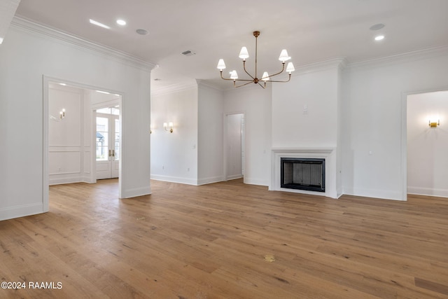 unfurnished living room featuring a chandelier, light wood-type flooring, ornamental molding, and a fireplace