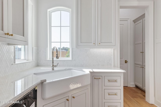 kitchen featuring light wood-type flooring, tasteful backsplash, and a sink