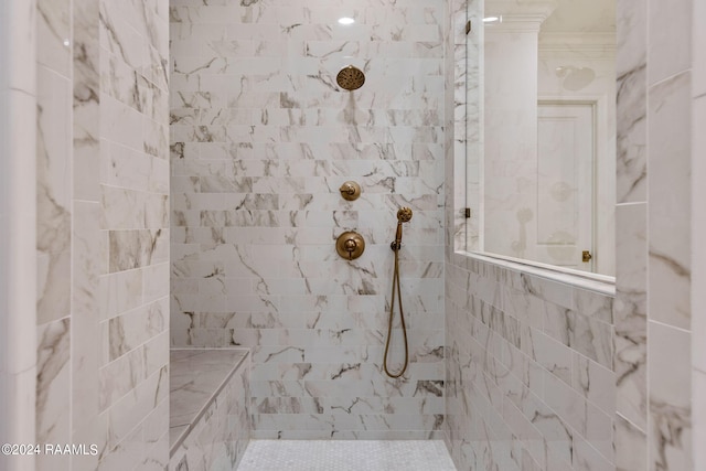 bathroom with ornamental molding and tiled shower