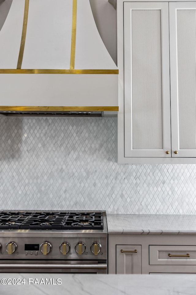 kitchen featuring light stone counters, white cabinets, open shelves, tasteful backsplash, and stainless steel range