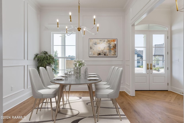 dining area featuring light hardwood / wood-style flooring, crown molding, a wealth of natural light, and french doors