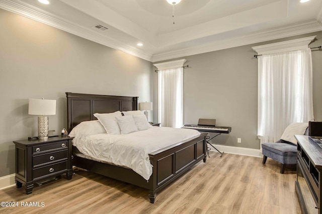 bedroom with ceiling fan, light hardwood / wood-style floors, crown molding, and a tray ceiling