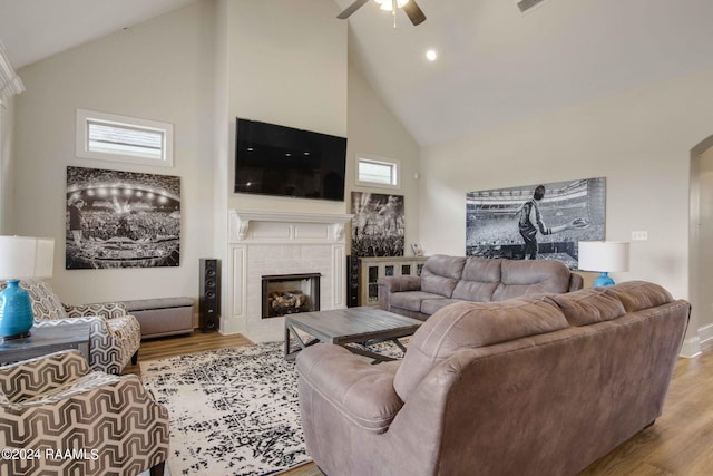 living room with a fireplace, wood-type flooring, ceiling fan, and high vaulted ceiling