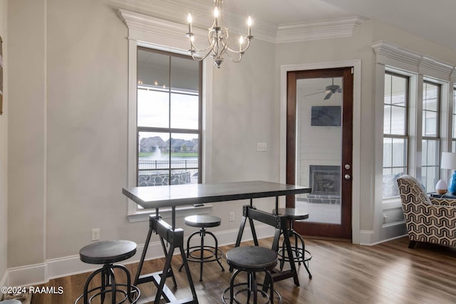 dining area with dark wood-type flooring, a chandelier, and ornamental molding