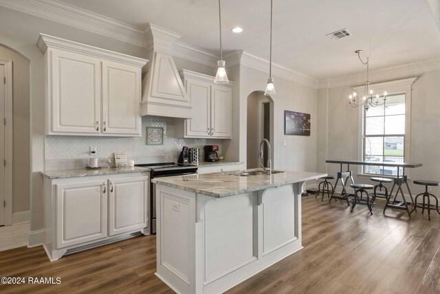 kitchen with electric stove, sink, hanging light fixtures, a kitchen island with sink, and hardwood / wood-style flooring