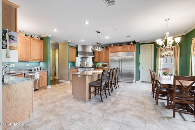 kitchen featuring a kitchen island, appliances with stainless steel finishes, hanging light fixtures, and wall chimney exhaust hood