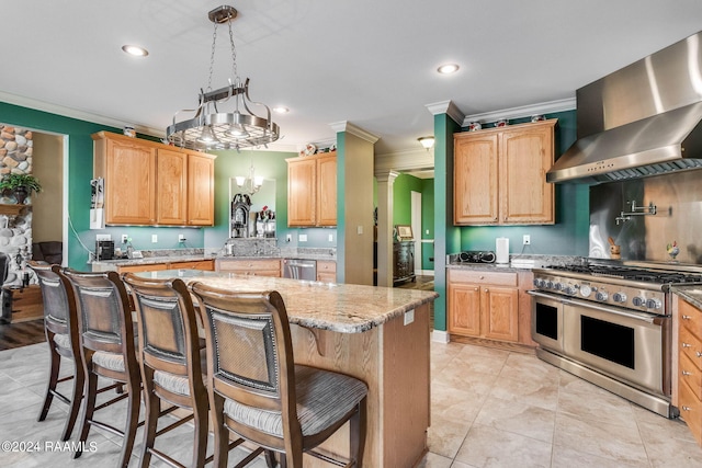 kitchen with decorative light fixtures, a center island, stainless steel appliances, light stone countertops, and wall chimney range hood