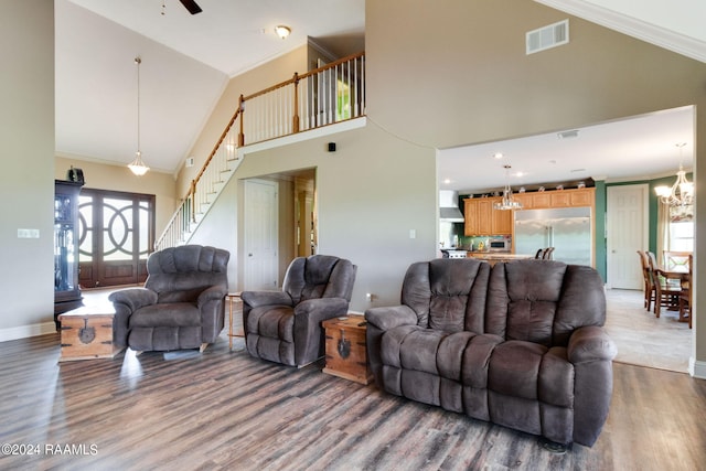 living room with an inviting chandelier, high vaulted ceiling, ornamental molding, and hardwood / wood-style floors